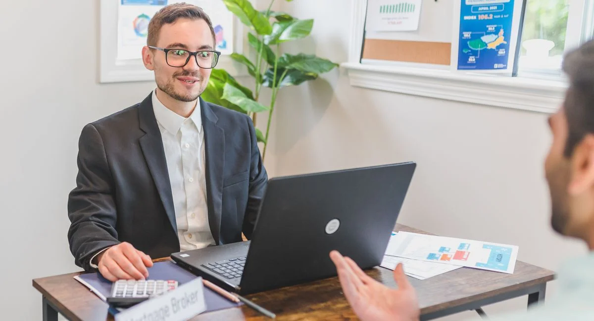 A mortgage broker and client discussing loan options in a modern office setting.