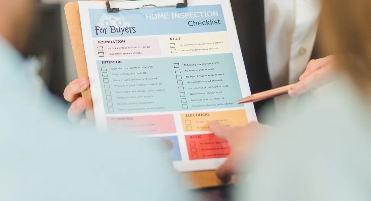 Close-up of hands holding a home inspection checklist clipboard for buyers.