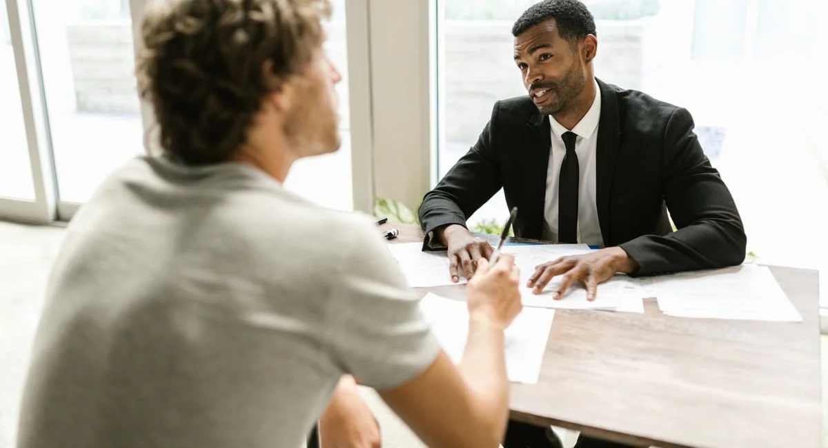 Two men having a discussion over documents in a modern office setting.