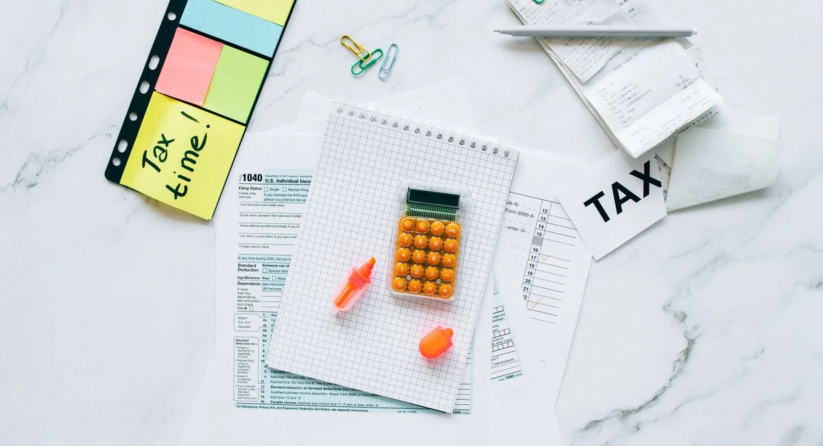 Flat lay of tax preparation essentials with calculator, forms, and colorful sticky notes.
