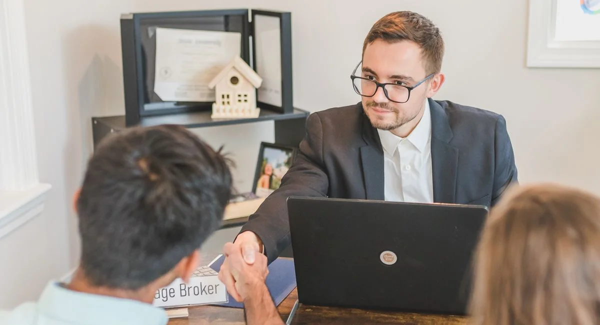 Business professionals in an office setting sealing a real estate deal through a handshake.