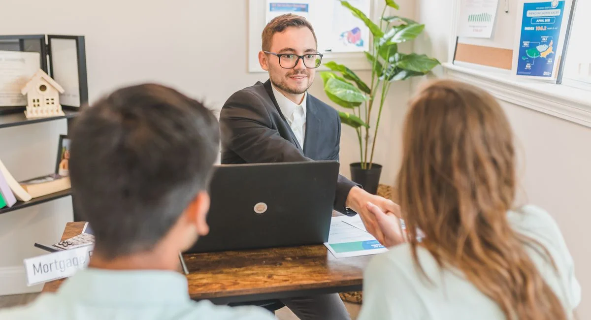 A mortgage broker meeting clients in an office, discussing agreements and loans.