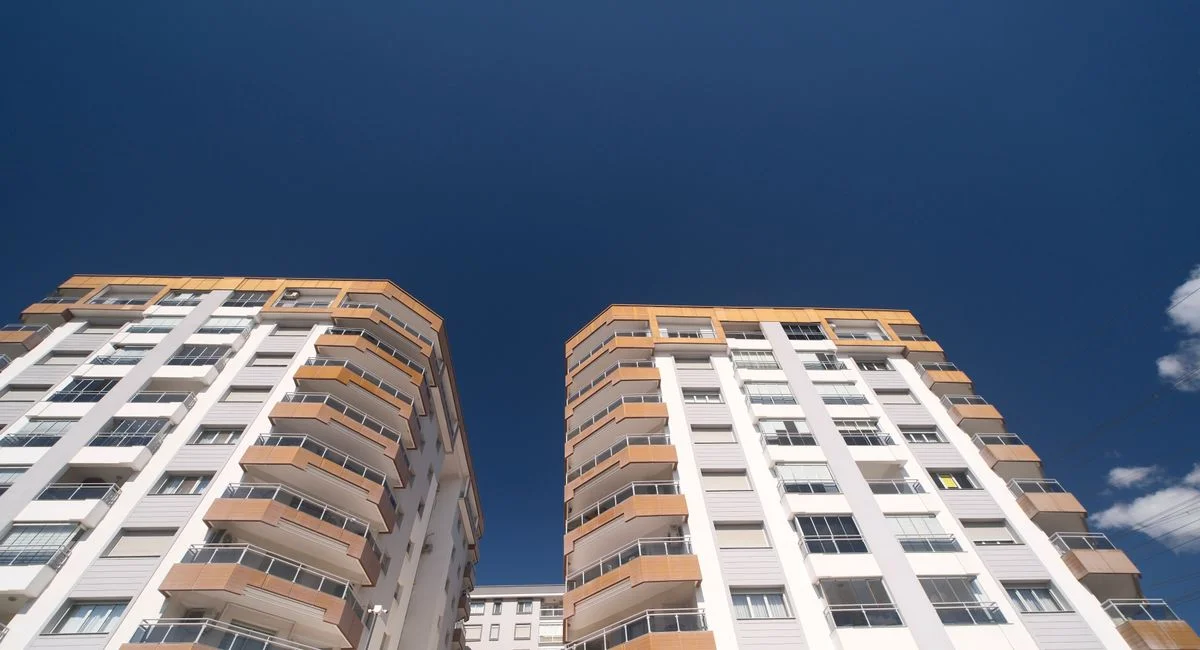 Low-angle view of modern residential buildings in İzmir, Türkiye under a clear blue sky.
