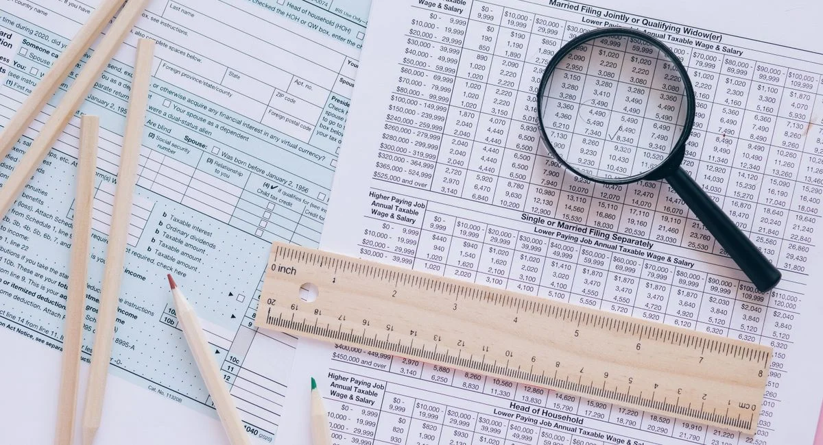 A high angle view showing IRS tax forms with pencils, ruler, and magnifying glass for financial planning.