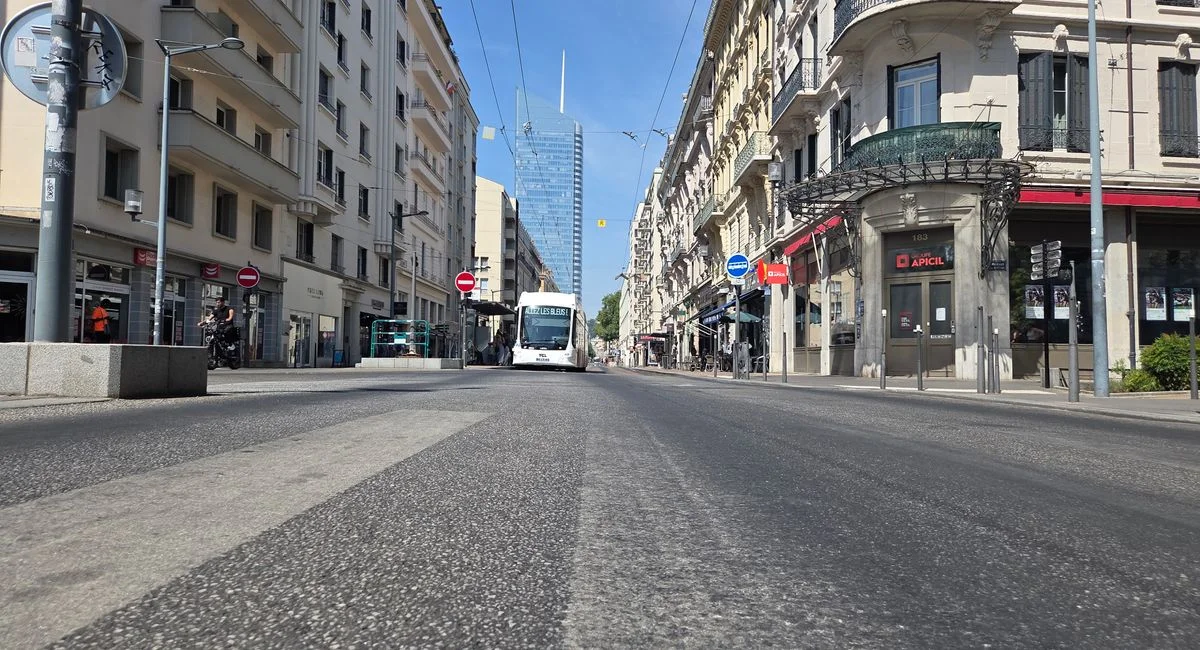 A low-angle street view of downtown Lyon featuring classic and modern architecture on a sunny day.