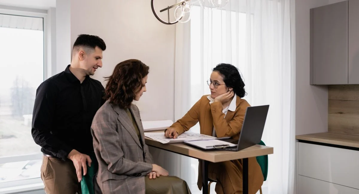 A couple consults a real estate agent in a modern office setting.