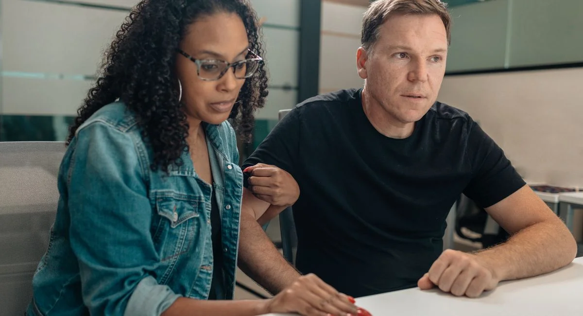 A couple closely examining paperwork in a modern office space. Focused and serious mood.