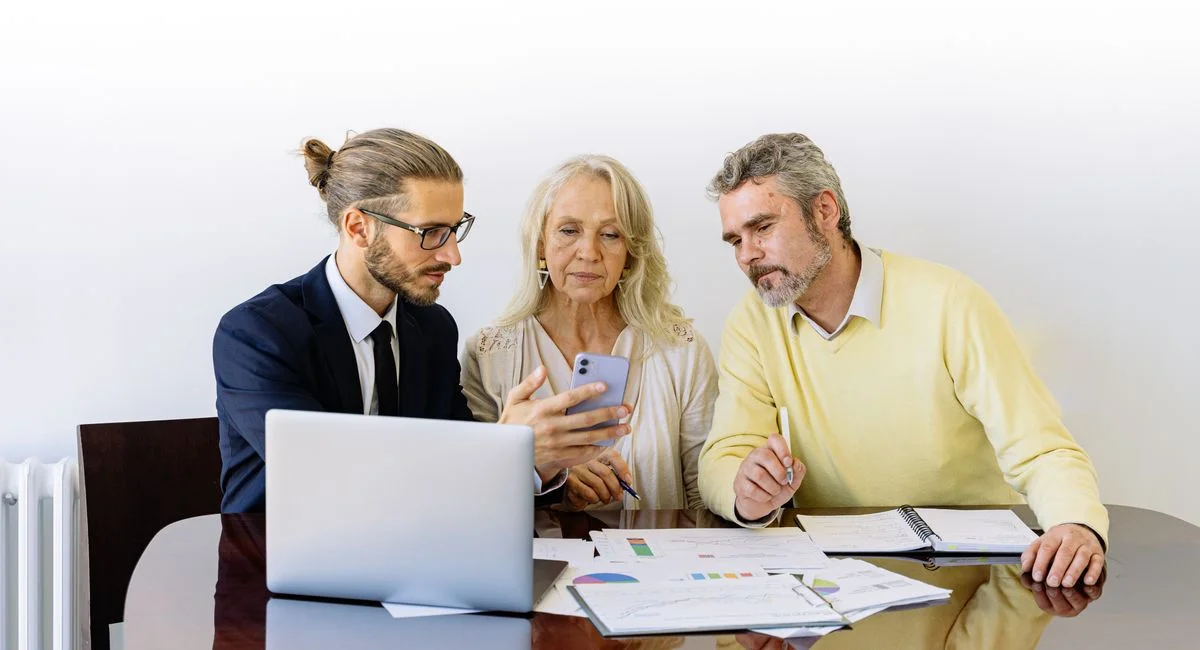 Three individuals collaborating on financial documents during a business meeting.