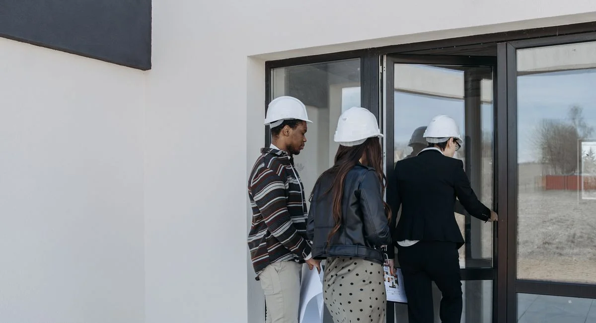 A group of diverse clients with a realtor at a new construction site entrance.