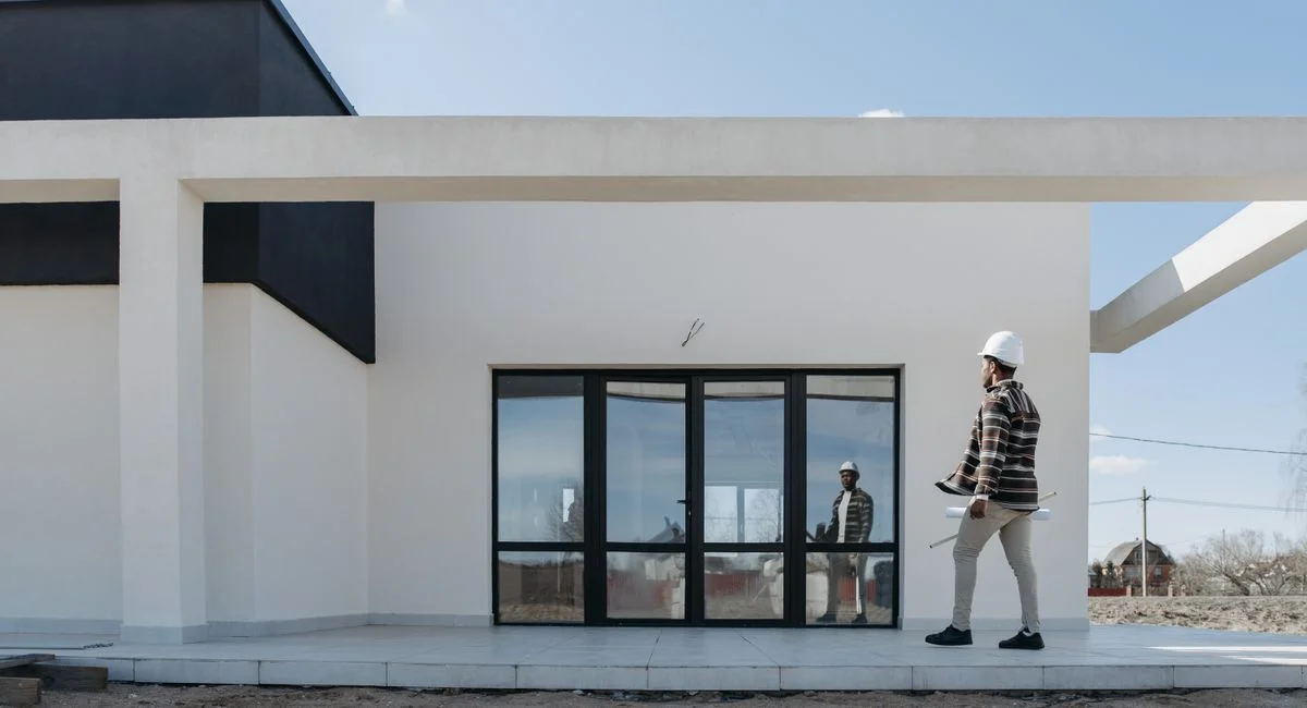 Architect with hard hat evaluating modern house exterior. Ideal for construction and architecture themes.