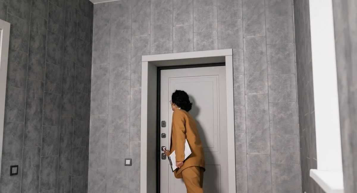 Real estate agent in business attire inspecting a modern home's entrance.