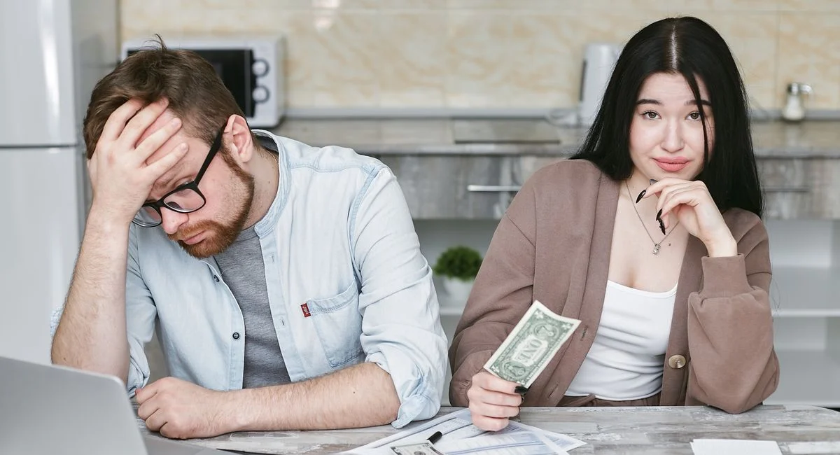 A couple managing their finances in a kitchen setting, showcasing money, debt, and budgeting challenges.