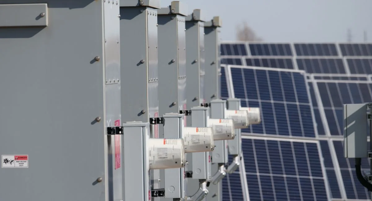 Close-up of electrical boxes and solar panels harnessing solar energy outdoors.