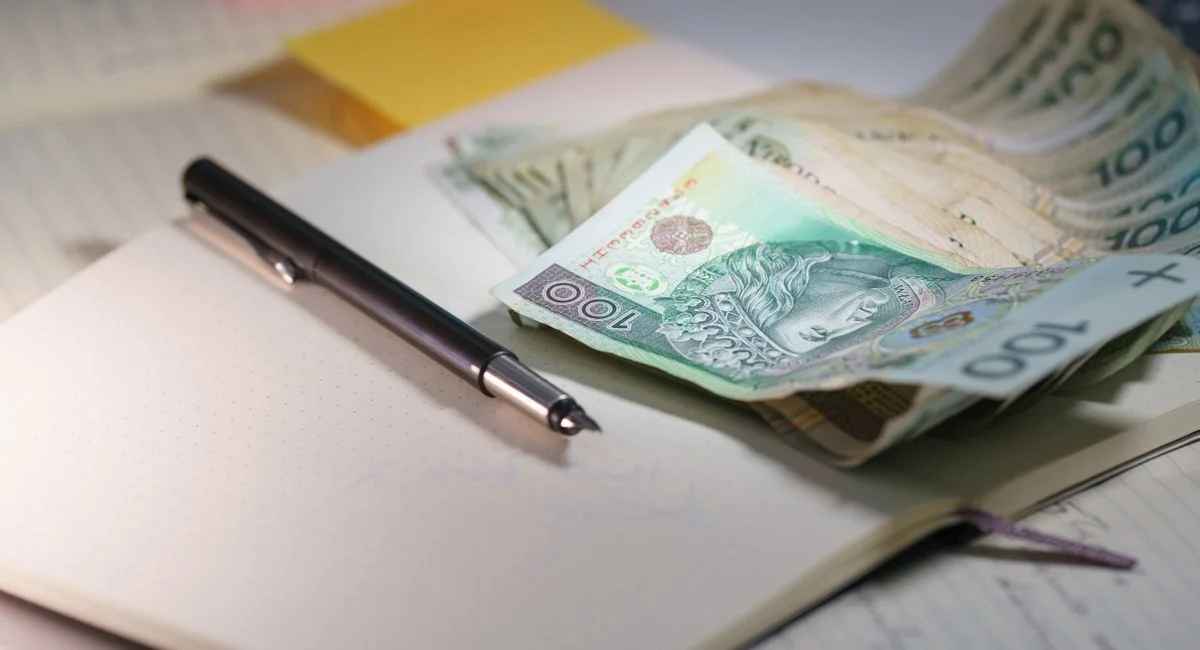 Close-up of Polish Zloty banknotes on an open notebook with a pen, symbolizing finance and budgeting.