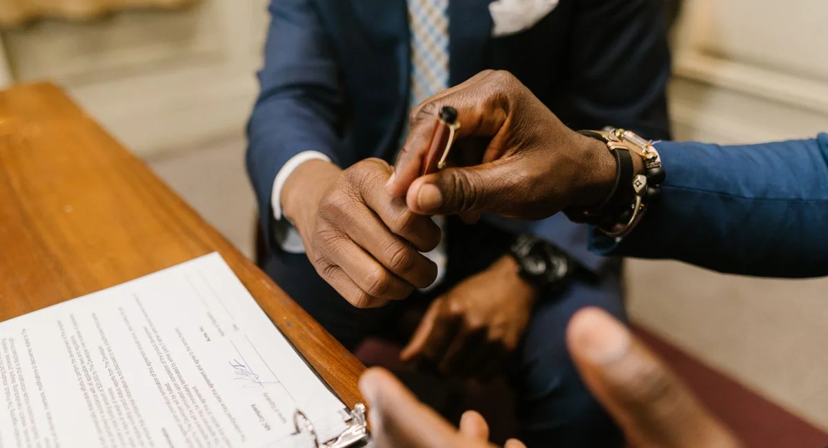 Two businessmen in suits finalize a contract, highlighting teamwork and agreement.